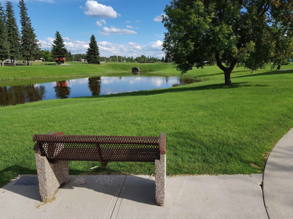 bench overlooking view of field and lake