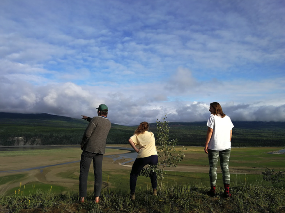 three friends enjoying the view of a field and mountains