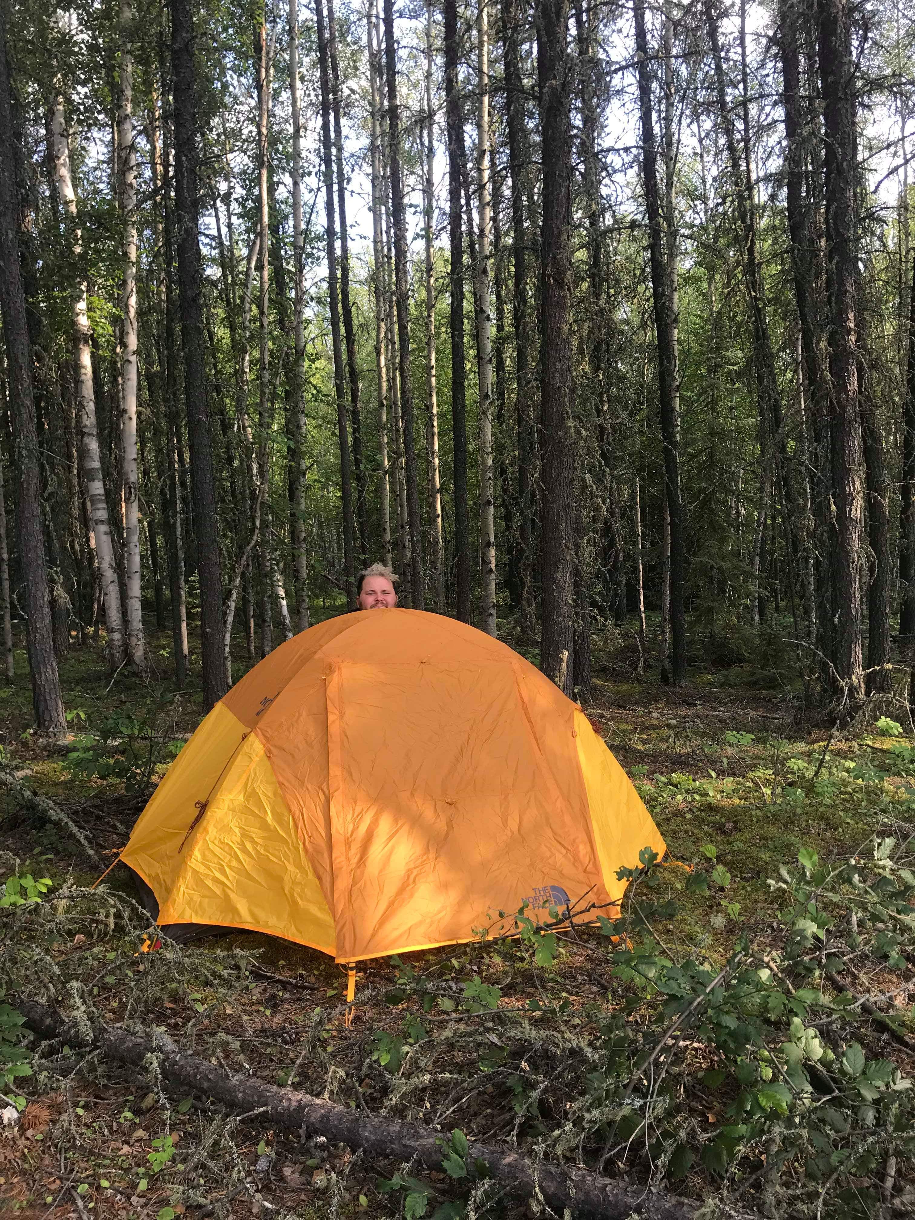 man standing behind orange tent